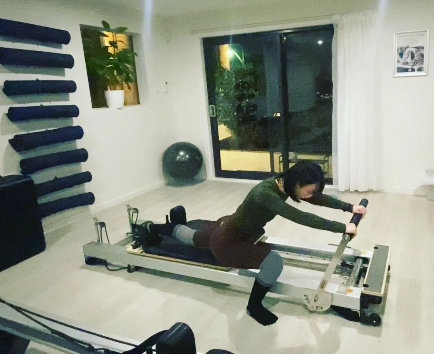 Single client training on a reformer in the evening-lit studio