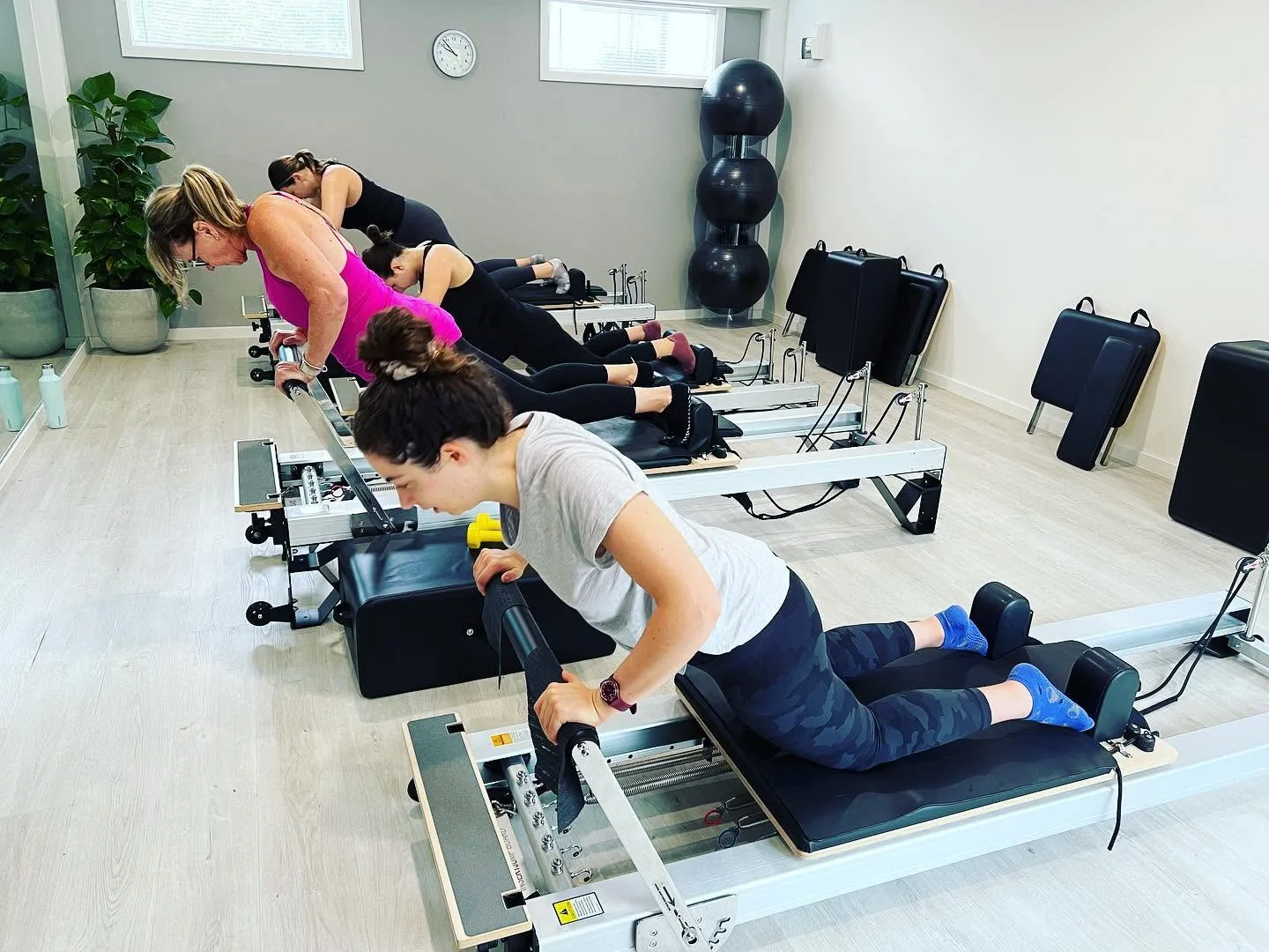 Reformer Pilates class in session, four clients planking on reformers