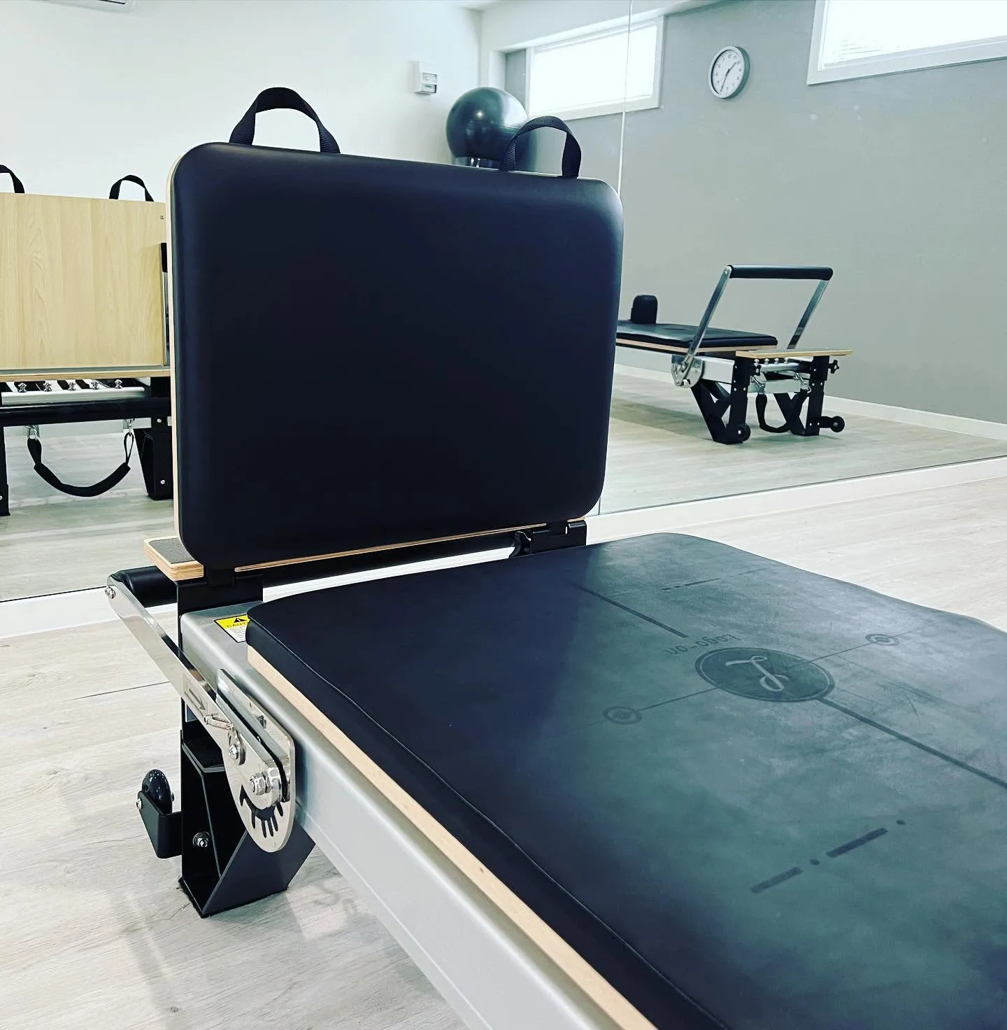 Reformer carriage and foot-bar detail with the studio mirrored behind