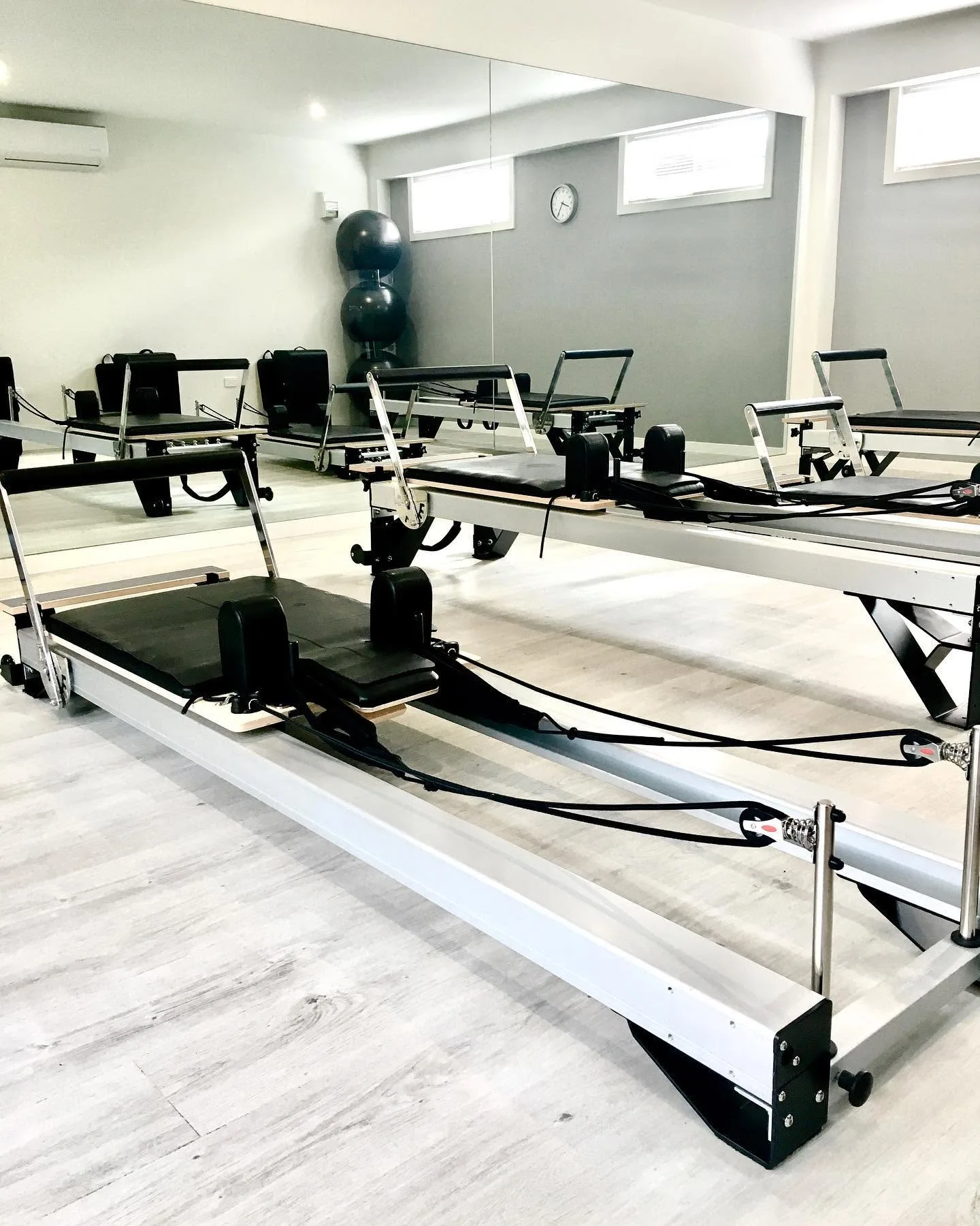 Aligned Health reformer studio — row of black reformers, mirror wall, stability balls