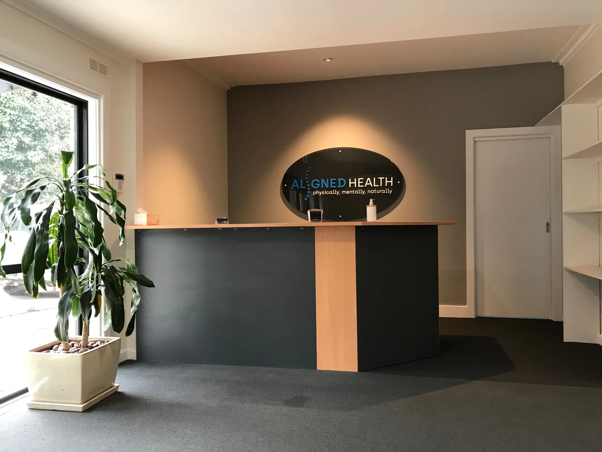 Aligned Health reception with the practice wordmark — physically, mentally, naturally